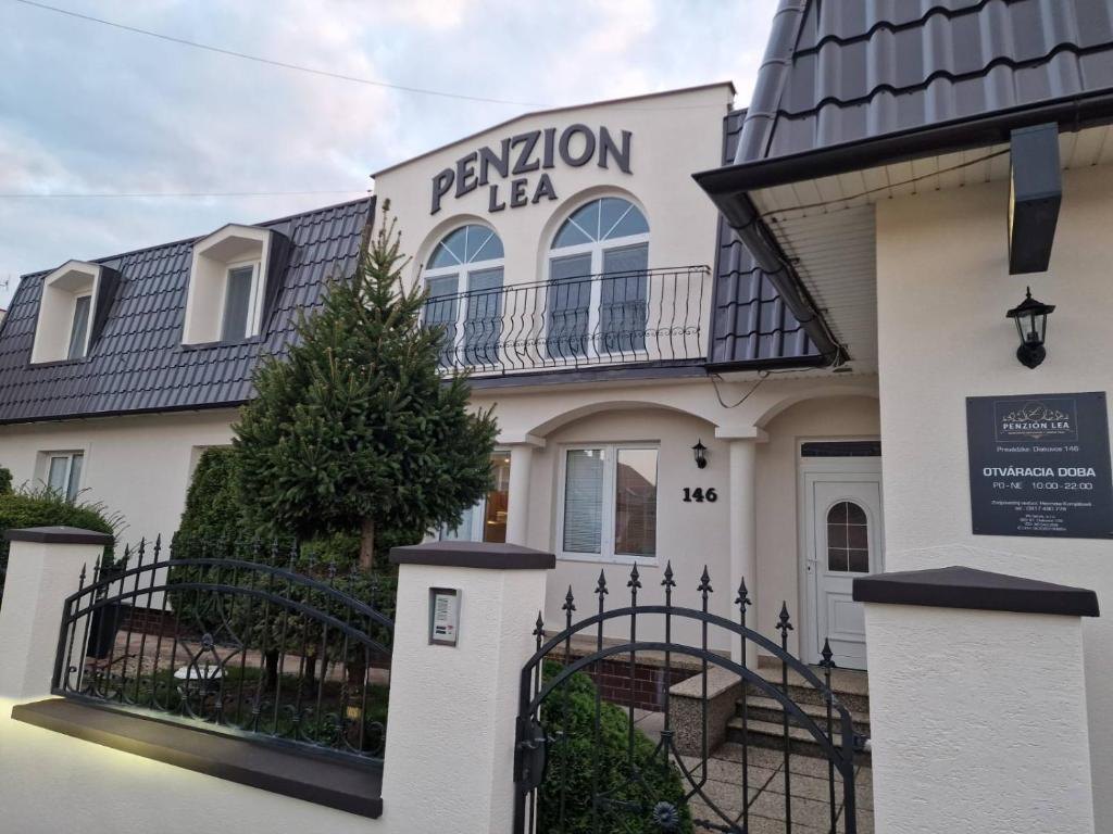Penzión Lea v Diakovciach — budova s balkónom, kovanou bránou a vzrastlým stromom pred vchodom